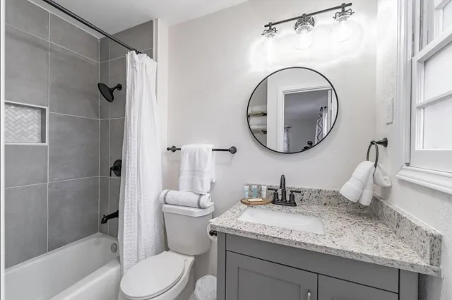 a bathroom with a granite countertop toilet sink and mirror