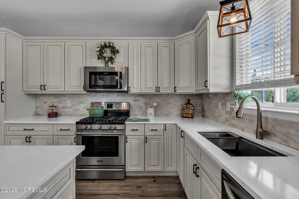 a kitchen with stainless steel appliances granite countertop a sink a stove and a microwave