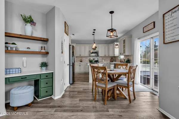 a kitchen with stainless steel appliances granite countertop a dining table chairs refrigerator and sink