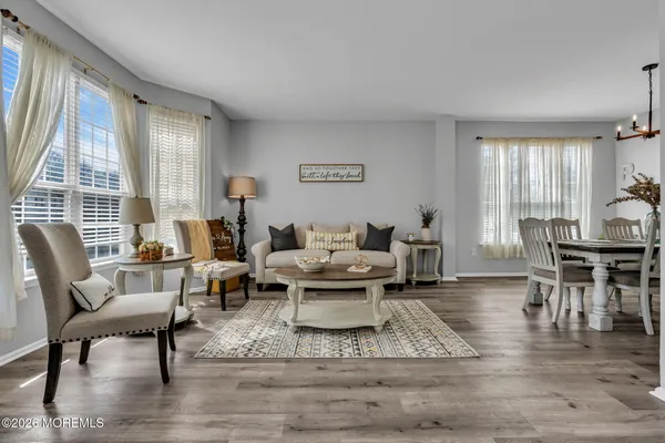 a living room with couches chairs and a dining table with wooden floor