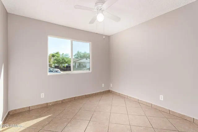 an empty room with a window and a fan