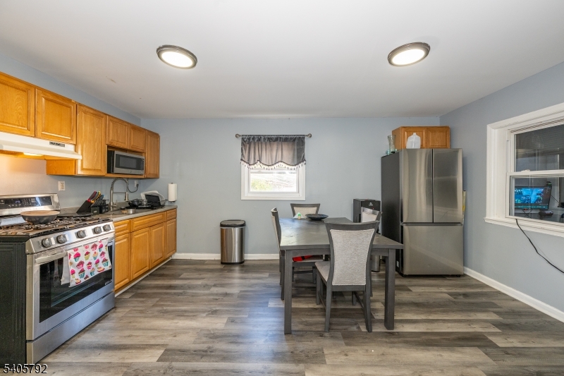 156 East Main Street Paterson, NJ 07522 - Photo 3 of 25 a kitchen with stainless steel appliances granite countertop a stove top oven a sink dishwasher a dining table and chairs with wooden floor