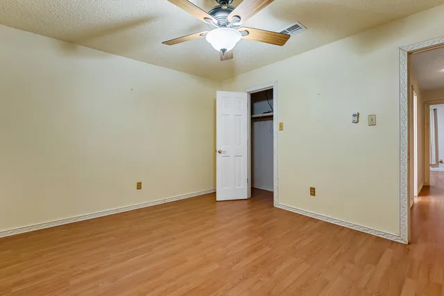 an empty room with closet and a ceiling fan