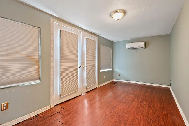 an empty room with wooden floor and windows