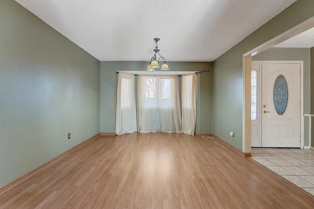 an empty room with wooden floor chandelier and windows