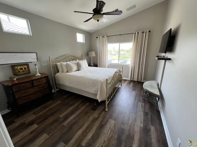 a bedroom with a bed wooden floor and flat screen tv