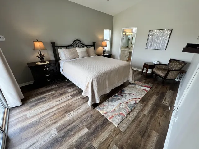 a bedroom with bed lamp and a mirror on dresser