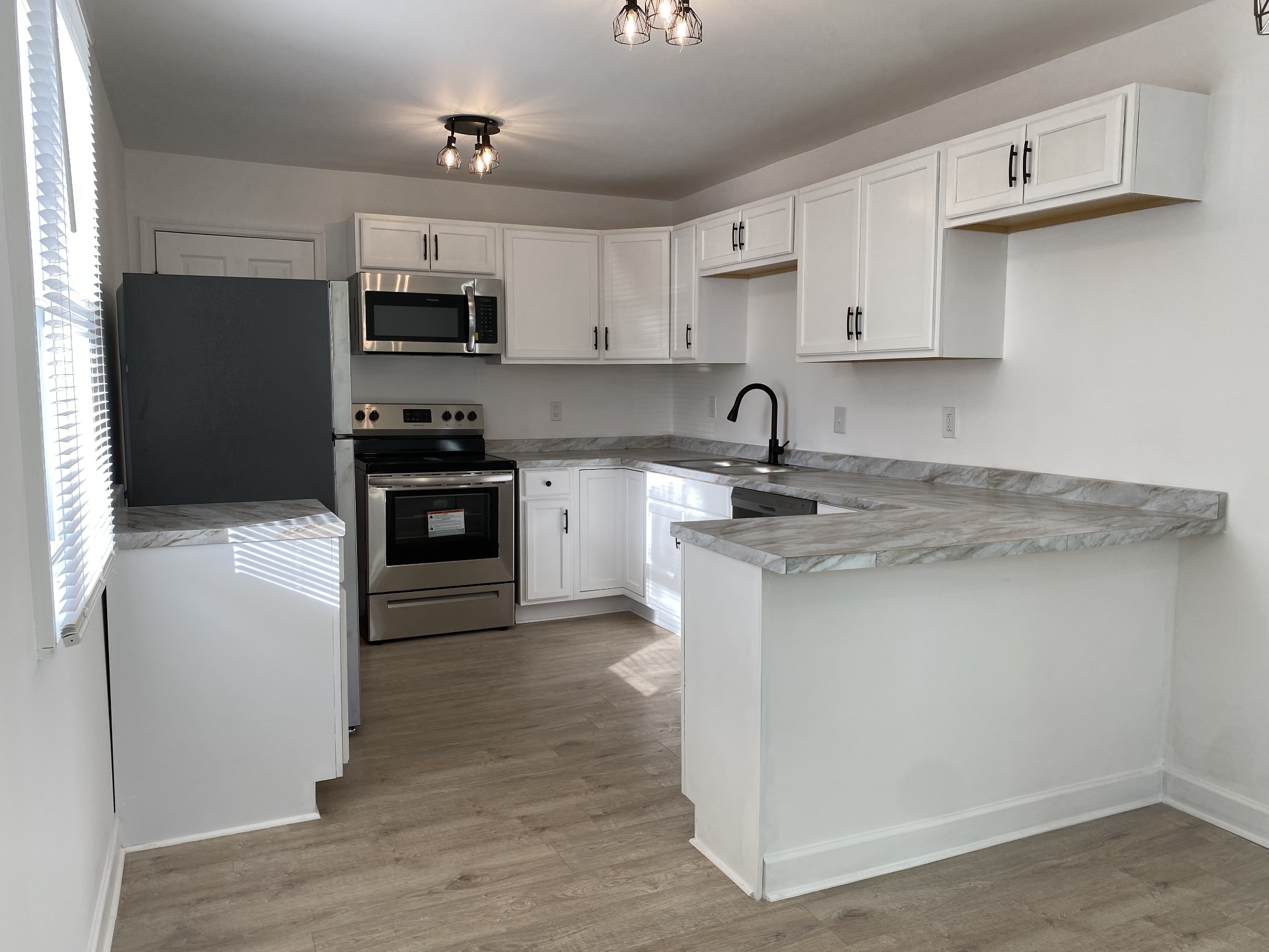 245 Raintree Drive Clarksville, TN 37042 - Photo 4 of 33 a kitchen with stainless steel appliances granite countertop white cabinets a sink a stove a microwave and wooden floor