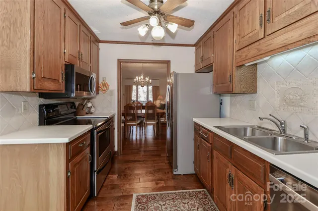 a kitchen with stainless steel appliances granite countertop a sink a stove oven a refrigerator with wooden cabinets and floor