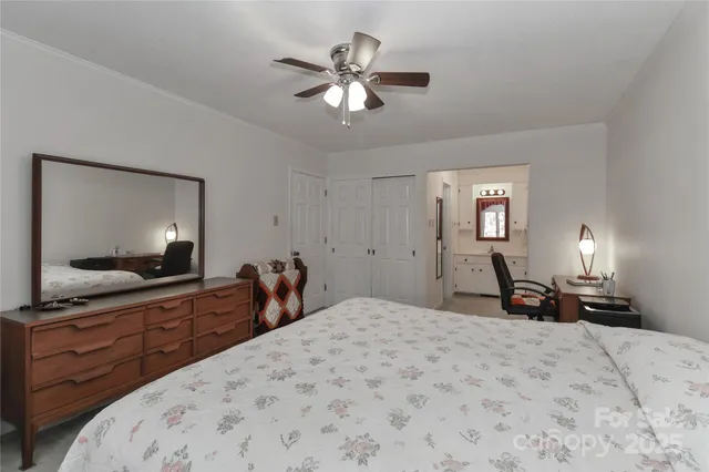 a bed room with a bed a mirror on dresser and a flat screen tv