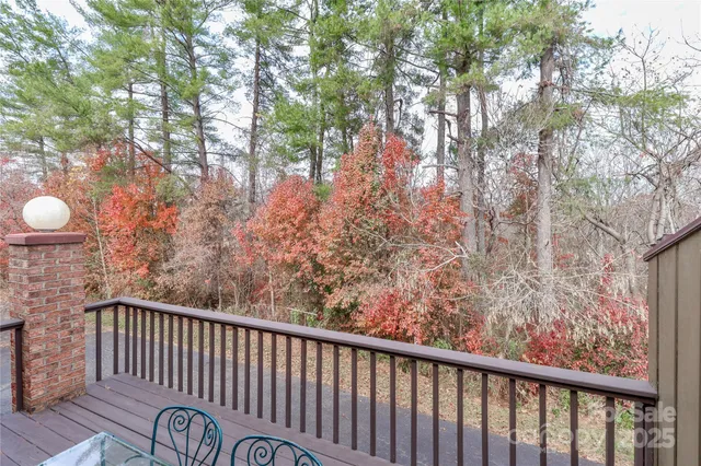 a view of roof deck with wooden fence and trees