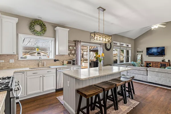 a large kitchen with granite countertop a table chairs sink and wooden floor