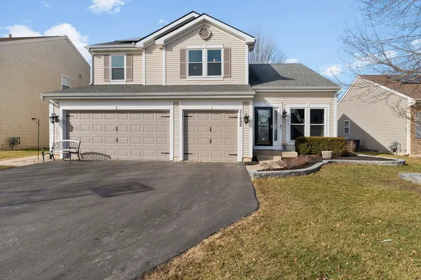 a front view of a house with yard and parking