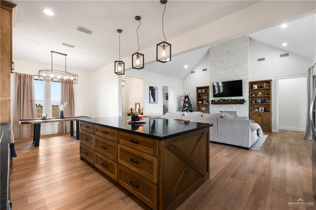 23588 Beefmaster Road Monte Alto, TX 78538 - Photo 13 of 45 a kitchen with stainless steel appliances granite countertop a stove a refrigerator a kitchen island a couches and couches with wooden floor