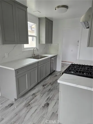 a kitchen with a sink a stove cabinets and wooden floor