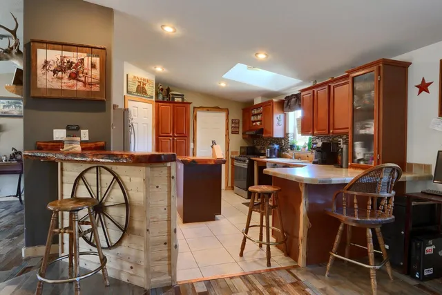 a kitchen with stainless steel appliances kitchen island granite countertop a table chairs in it and wooden floors