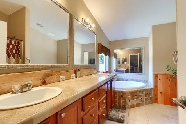 a bathroom with a tub double sink window and mirror