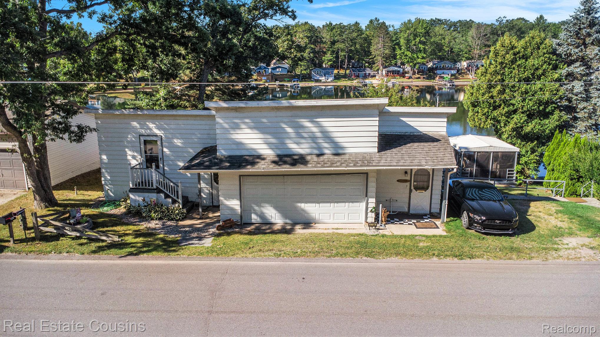 1734 Forest Road Harrison, MI 48625 - Photo 28 of 31 View of front of property featuring roof with shingles, an attached garage, and a water view