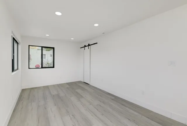 a view of an empty room with a window and wooden floor