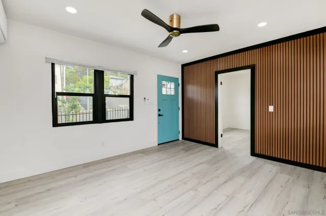 a view of an empty room with a window and wooden floor