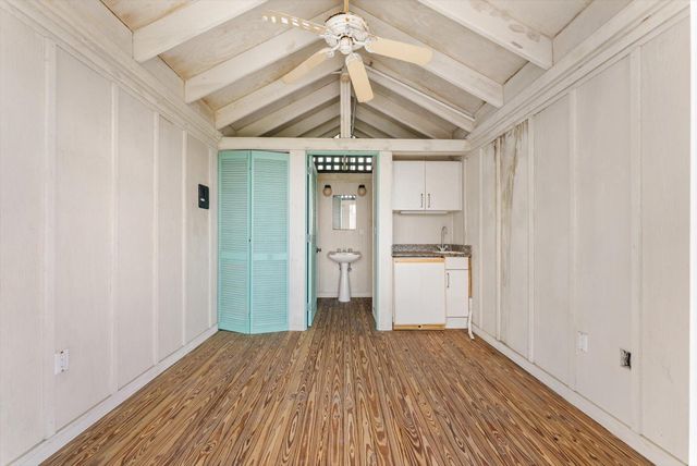 a view of a hallway with wooden floor and a ceiling fan
