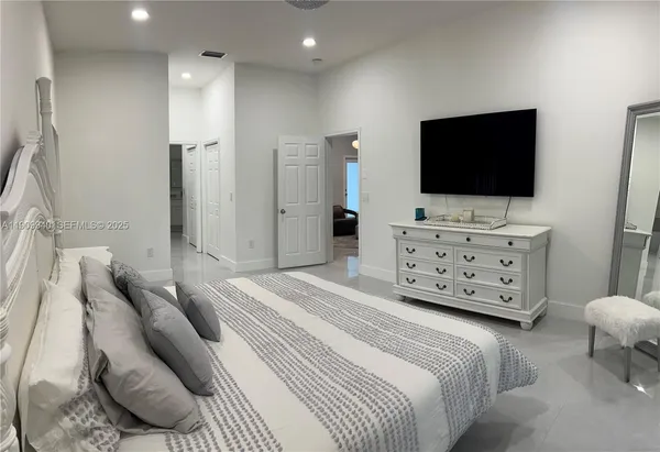 a spacious bedroom with a bed and a flat screen television