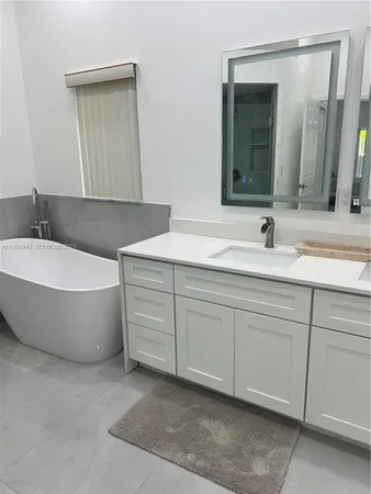 a spacious bathroom with a double vanity sink mirror and bathtub