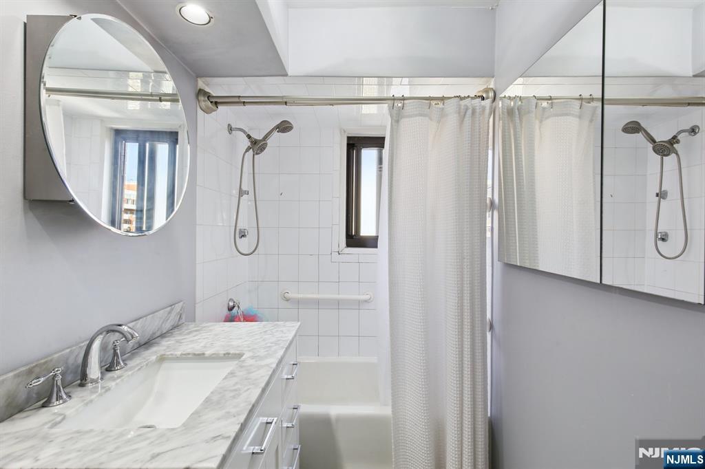 125 Prospect Avenue, Unit 17G Hackensack, NJ 07601 - Photo 16 of 20 a bathroom with a granite countertop sink a mirror a vanity and shower