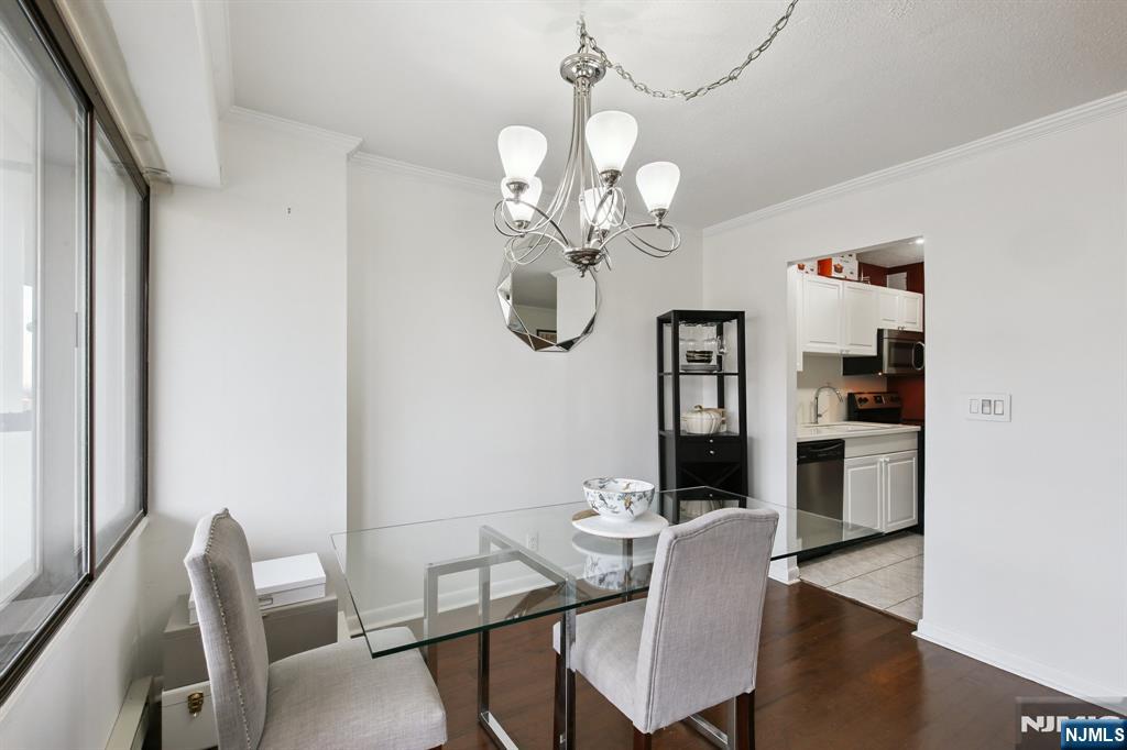 125 Prospect Avenue, Unit 17G Hackensack, NJ 07601 - Photo 7 of 20 a dining room with wooden floor a chandelier a wooden table and chairs