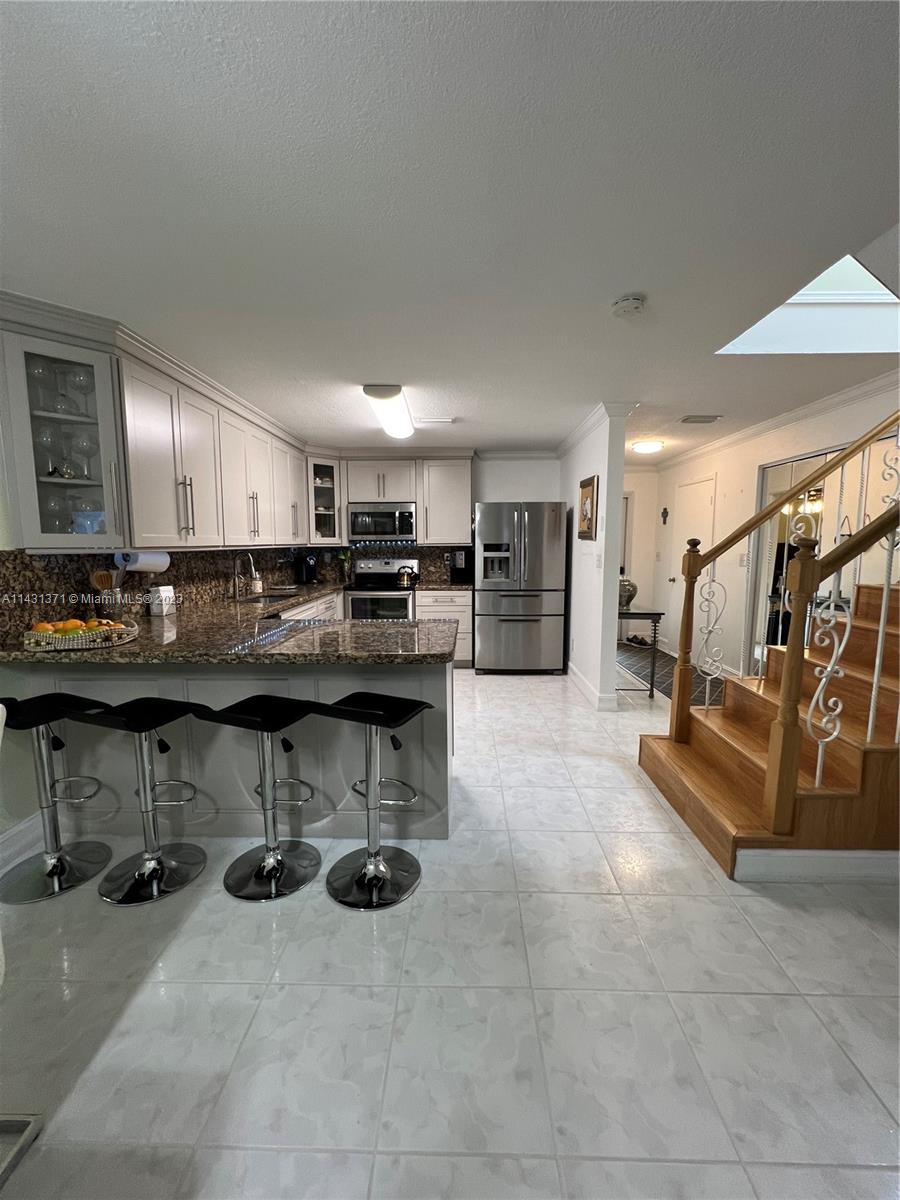 23314 Southwest 54th Way, Unit E Boca Raton, FL 33433 - Photo 42 of 69 a kitchen with stainless steel appliances kitchen island granite countertop a table and chairs in it