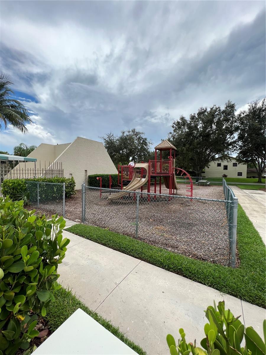 23314 Southwest 54th Way, Unit E Boca Raton, FL 33433 - Photo 6 of 69 a view of a garden with a bench in front of the house