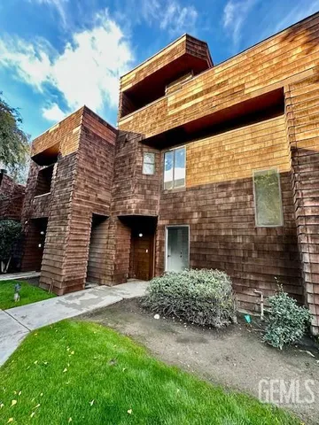 a view of a brick house with a small yard and wooden fence