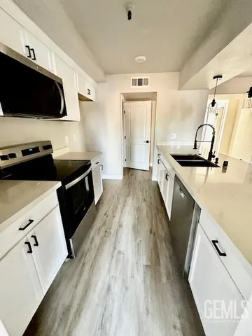 a kitchen with granite countertop a stove a sink and a microwave