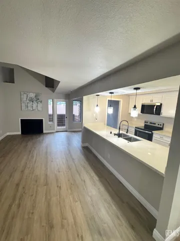 a large white kitchen with stainless steel appliances a large window and wooden floor