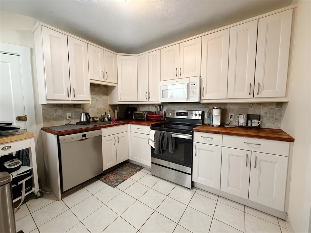 1472 Commonwealth Avenue, Unit 2 Boston, MA 02135 - Photo 2 of 16 a kitchen with granite countertop white cabinets and white appliances