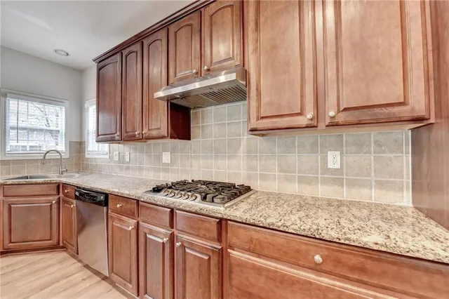 a kitchen with granite countertop wooden cabinets a sink and dishwasher