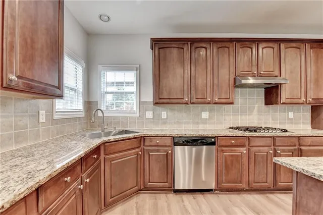 a large kitchen with stainless steel appliances granite countertop a stove a sink dishwasher and a refrigerator with wooden floor