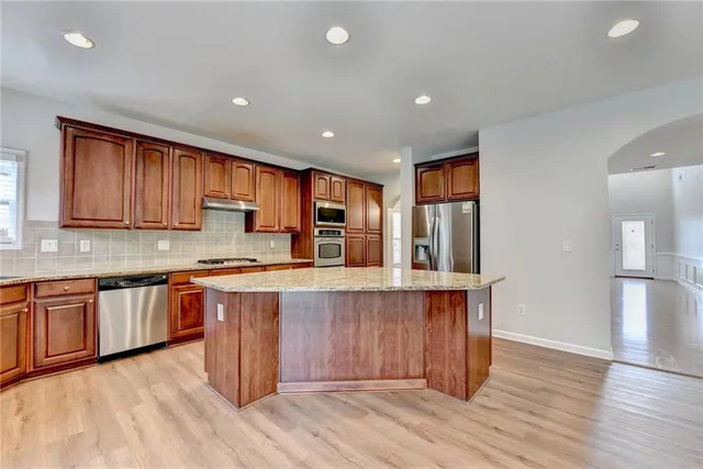 a large kitchen with stainless steel appliances wooden floors and wooden cabinets