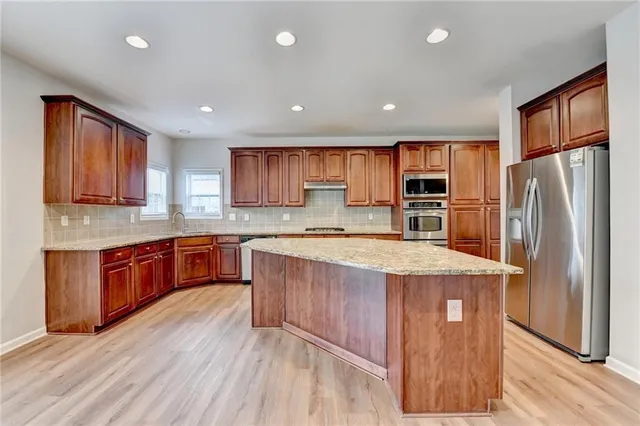 a large kitchen with stainless steel appliances granite countertop a stove a sink and a refrigerator