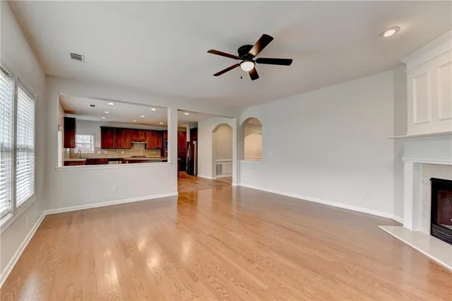 a view of an empty room with window and kitchen view