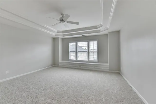 an empty room with a chandelier fan and windows