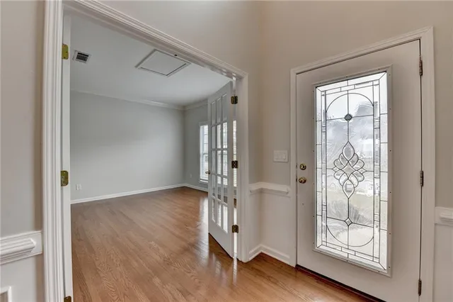 a view of an empty room with wooden floor and a window