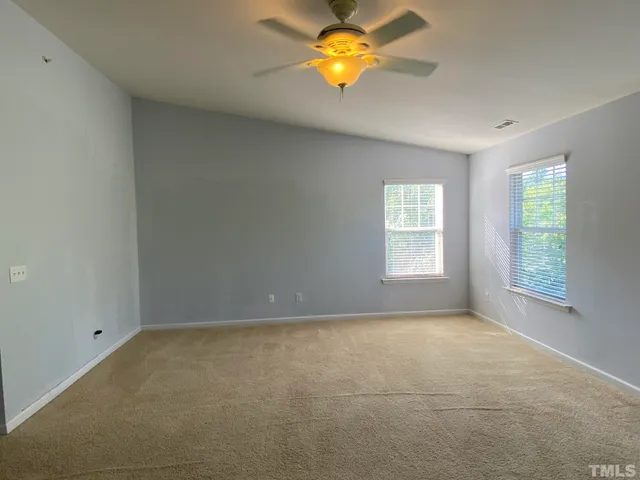 an empty room with a window and chandelier fan