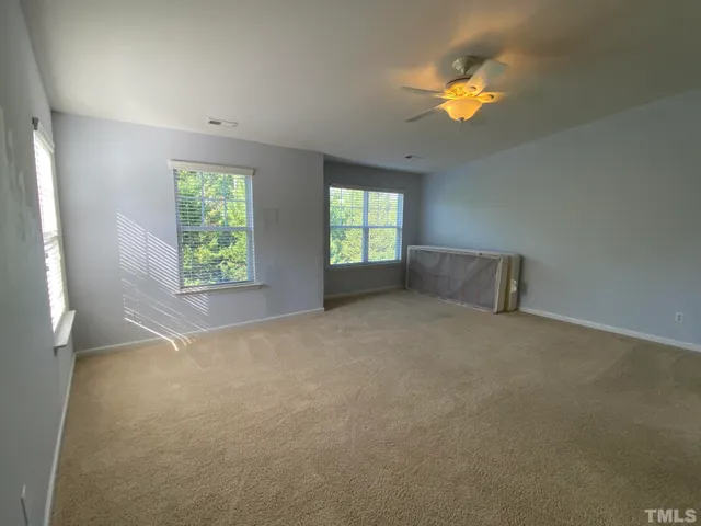 an empty room with windows and ceiling fan