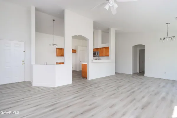 a view of a kitchen with wooden floor and white cabinets