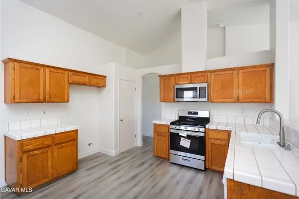 a kitchen with stainless steel appliances granite countertop a stove a sink and a microwave