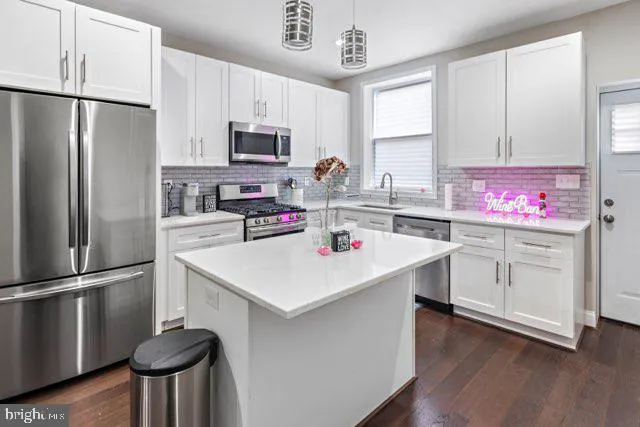 a kitchen with kitchen island a white cabinets and stainless steel appliances