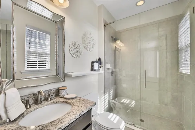 a bathroom with a granite countertop sink a toilet and a mirror