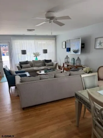 a living room with stainless steel appliances kitchen island granite countertop furniture and a wooden floor