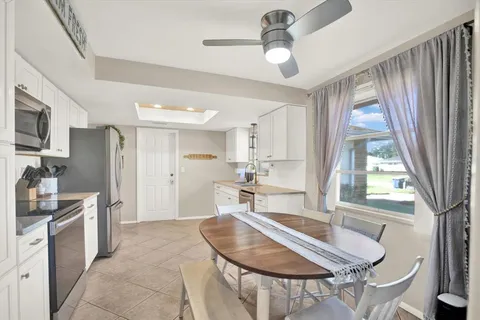 a kitchen with stainless steel appliances granite countertop a stove a refrigerator a sink a dining table and chairs with wooden floor